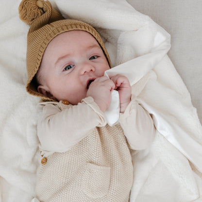 Baby snuggling with a cozy and soft, white satin border mini blanket. 