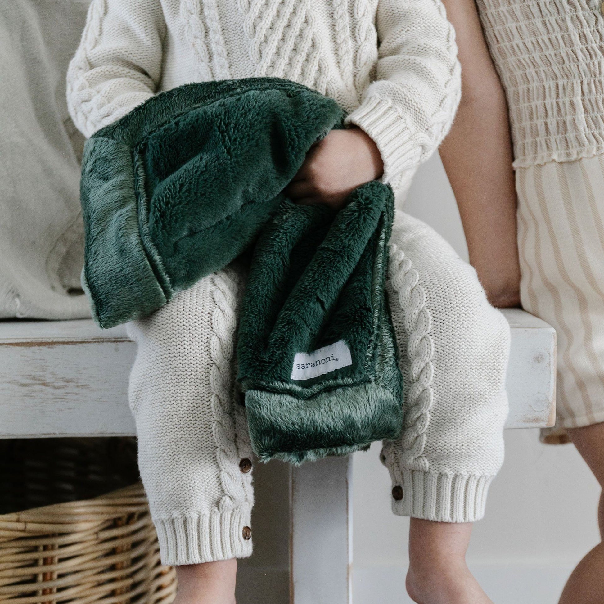 A little boy holds a Hunter Green Colored Lush Saranoni Blanket. The soft blanket is a small blanket and a baby blanket or toddler blanket.