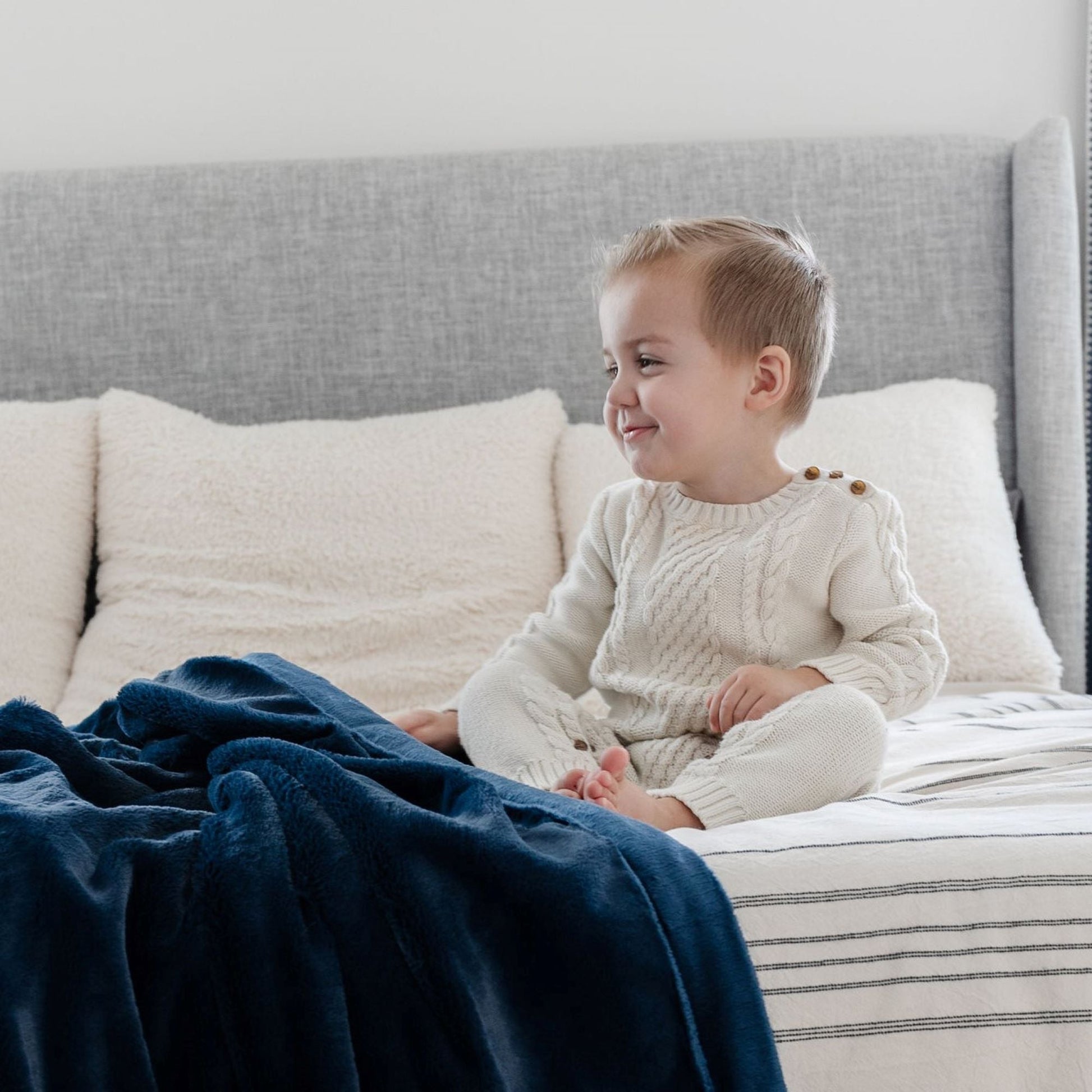 A little boy sits by a Luxury Receiving Navy Colored Lush Saranoni Blanket. The soft blanket is a small blanket and a baby blanket or toddler blanket.