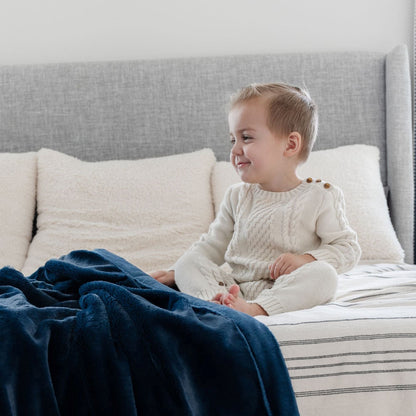 A little boy sits by a Luxury Receiving Navy Colored Lush Saranoni Blanket. The soft blanket is a small blanket and a baby blanket or toddler blanket.