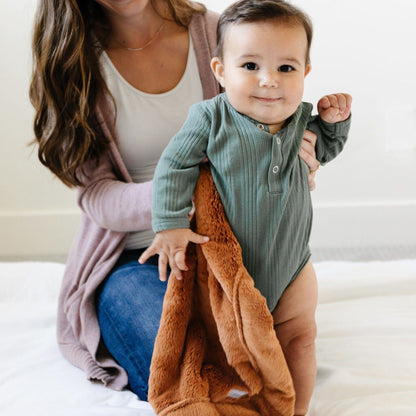 A baby boy has a Camel Colored Lush Saranoni Blanket. The soft blanket is a small blanket and a baby blanket or toddler blanket.