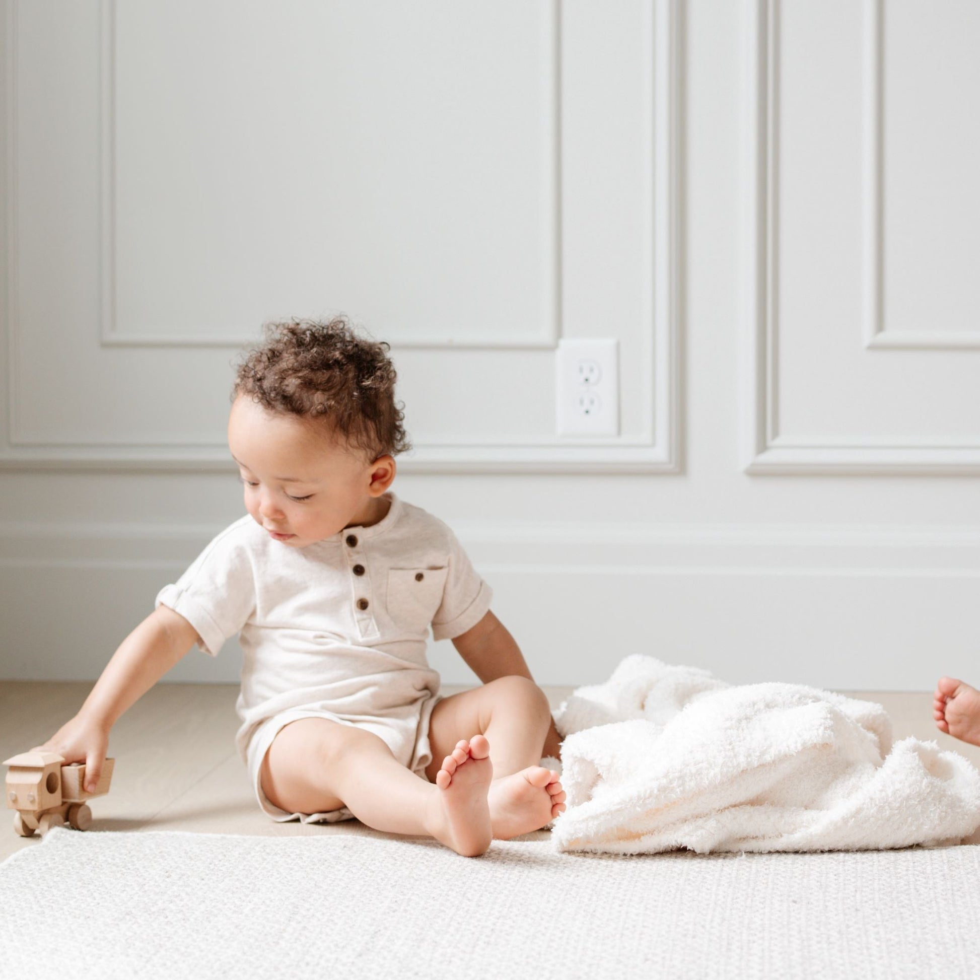 Babies playing on the floors with wooden toys and beautiful, ivory BAMBONI RECEIVING BLANKETS - Saranoni