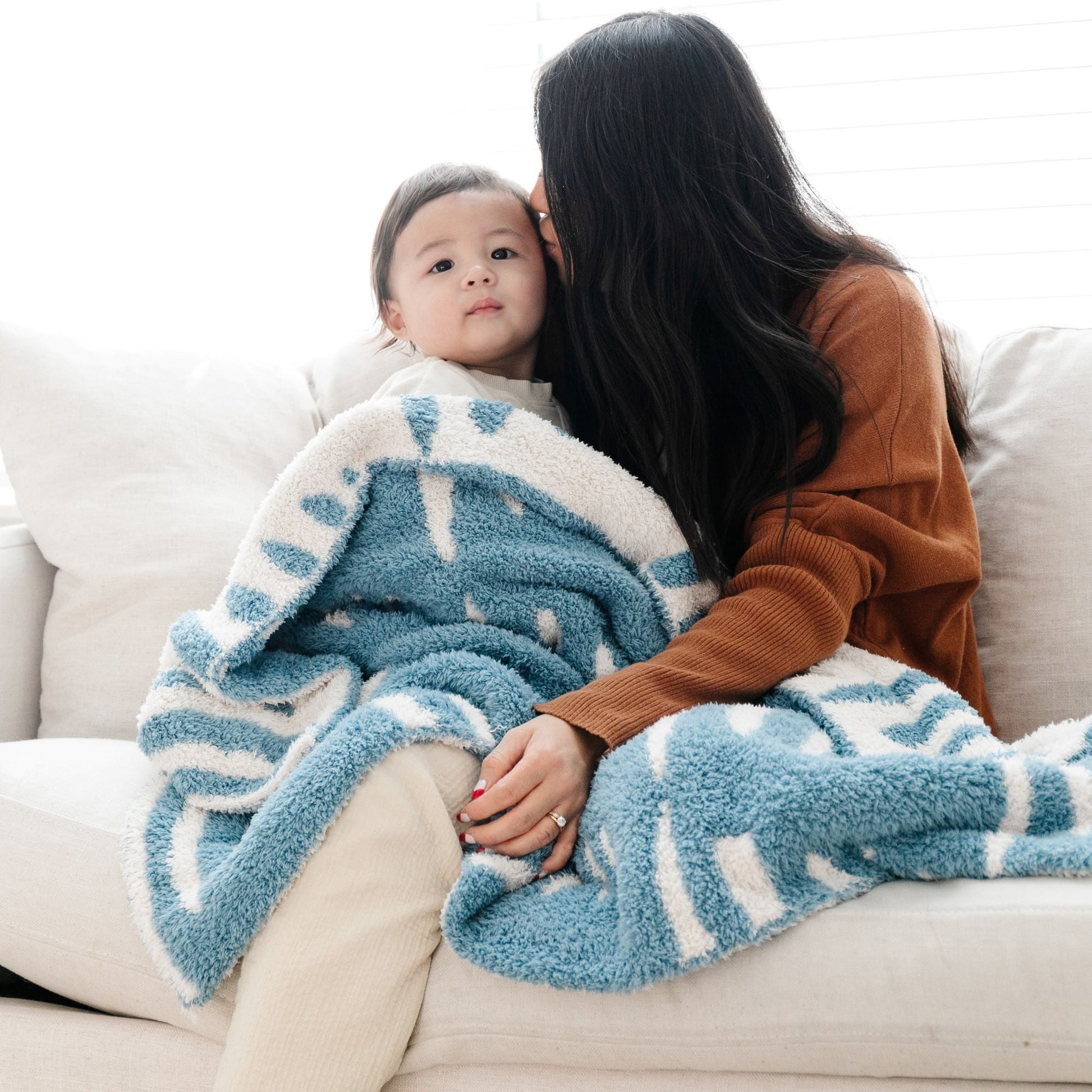 Mom kissing little kid's forehead, wrapped in beautiful and soft Blue + White Stripe Triangle DOUBLE-LAYER BAMBONI TODDLER BLANKETS - Saranoni
