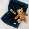 Navy@A picture of a teddy bear and toy sitting on a navy blue faux fur blanket.
