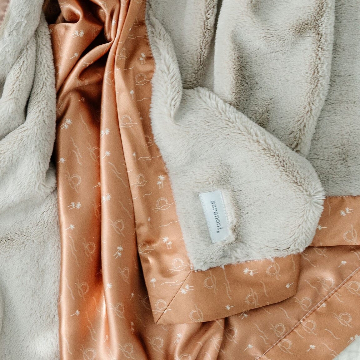 Receiving blanket with a gentle, plush front and a satin back, providing a cozy and elegant wrap for your little one.